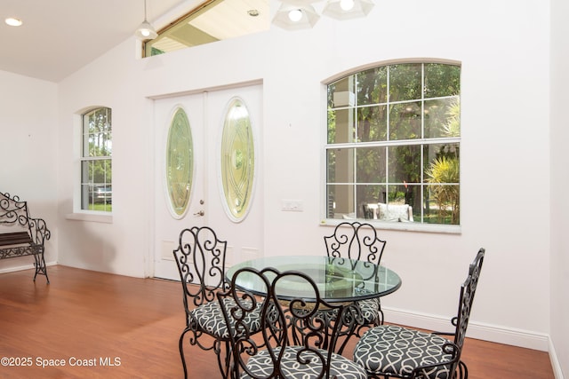 7030 Livingstone Ln, Melbourne, FL 32904 - dining space featuring wood finished floors, vaulted ceiling, and baseboards