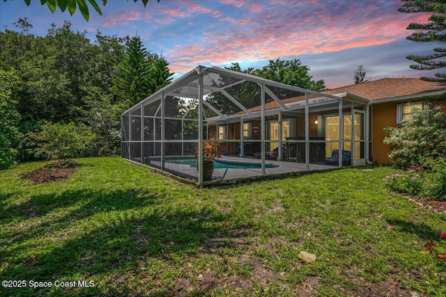 965 19th St SW, Vero Beach, FL 32962 - back of property at dusk with an outdoor pool, a yard, a patio area, and a lanai