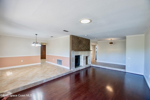 5510 Howell Branch Rd, Winter Park, FL 32792 - unfurnished living room featuring a chandelier, wood finished floors, ornamental molding, a tiled fireplace, and a textured ceiling