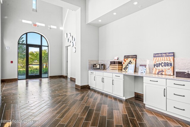 8854 Alister Dr, Melbourne, FL 32940 - interior space with a high ceiling, baseboards, light stone countertops, recessed lighting, and white cabinetry