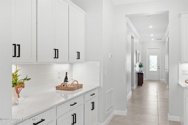 8854 Alister Dr, Melbourne, FL 32940 - bar area with ornamental molding, baseboards, decorative backsplash, and light tile patterned floors