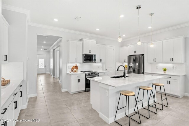 8854 Alister Dr, Melbourne, FL 32940 - kitchen featuring appliances with stainless steel finishes, a sink, backsplash, a breakfast bar, and white cabinets