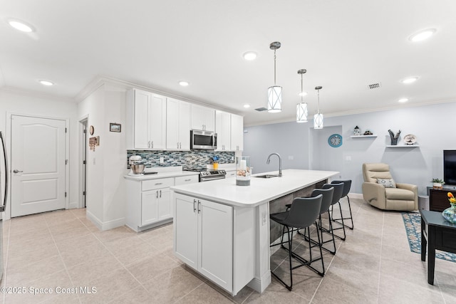 916 Corbin Cir SW, Palm Bay, FL 32908 - kitchen featuring stainless steel appliances, a sink, crown molding, light tile patterned flooring, and a kitchen breakfast bar