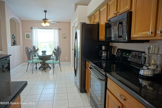 kitchen with black appliances, brown cabinetry, dark stone counters, and light tile patterned floors