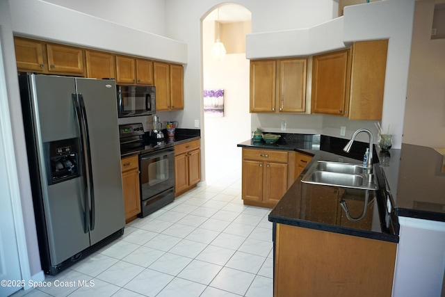 kitchen with black appliances, a sink, brown cabinets, a peninsula, and a high ceiling
