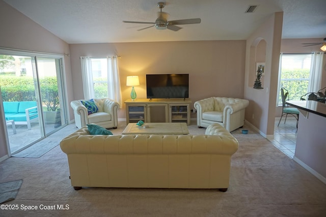 living area featuring a ceiling fan, light colored carpet, plenty of natural light, and lofted ceiling