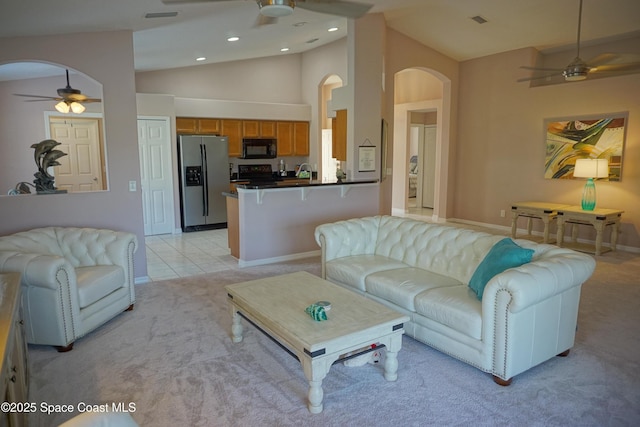 living room with ceiling fan, arched walkways, light carpet, lofted ceiling, and baseboards