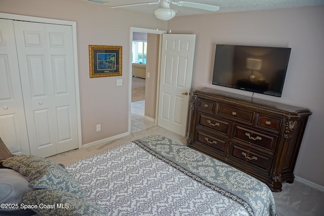bedroom with light colored carpet, baseboards, a ceiling fan, and a closet