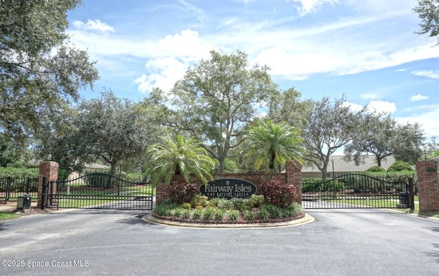 view of asphalt street featuring a gate, a gated entry, and curbs