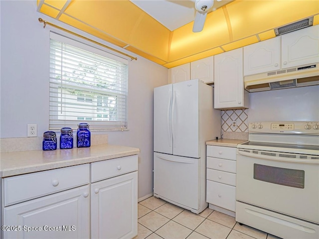 18 Vista Palm Ln Unit 102, Vero Beach, FL 32962 - kitchen featuring white appliances, under cabinet range hood, light tile patterned flooring, and white cabinets