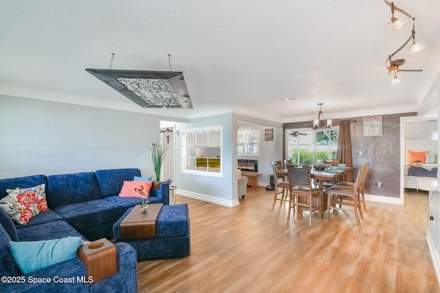 1029 Palmer Rd, Rockledge, FL 32955 - living area with light wood finished floors, rail lighting, a textured ceiling, and a glass covered fireplace