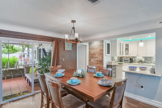 1029 Palmer Rd, Rockledge, FL 32955 - dining space with a chandelier, wood finished floors, and a textured ceiling