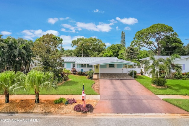 1029 Palmer Rd, Rockledge, FL 32955 - view of front of house with a front yard, an attached carport, concrete driveway, and a metal roof