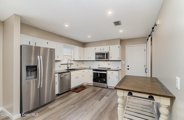 5460 Holden Rd, Cocoa, FL 32927 - kitchen featuring appliances with stainless steel finishes, a sink, light wood-style flooring, white cabinets, and tasteful backsplash