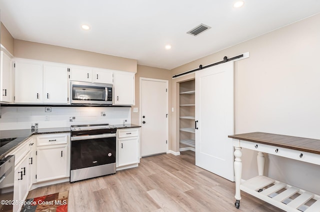 5460 Holden Rd, Cocoa, FL 32927 - kitchen featuring appliances with stainless steel finishes, dark countertops, a barn door, white cabinets, and recessed lighting
