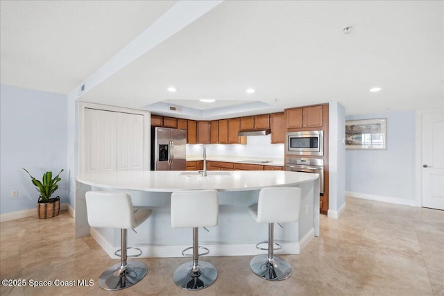 121 Lancha Cir Unit 206, Indian Harbour Beach, FL 32937 - kitchen with stainless steel appliances, a sink, brown cabinets, light countertops, and a breakfast bar