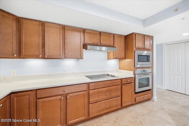121 Lancha Cir Unit 206, Indian Harbour Beach, FL 32937 - kitchen featuring appliances with stainless steel finishes, under cabinet range hood, brown cabinets, a raised ceiling, and baseboards