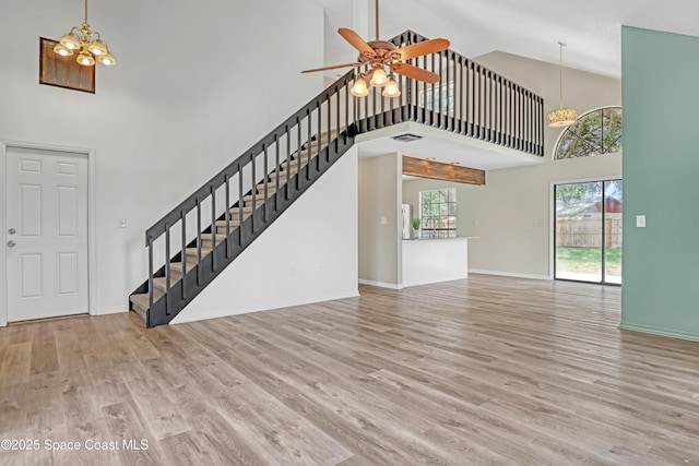 6827 Dodge Rd, Cocoa, FL 32927 - unfurnished living room with high vaulted ceiling, stairs, a ceiling fan, wood finished floors, and baseboards