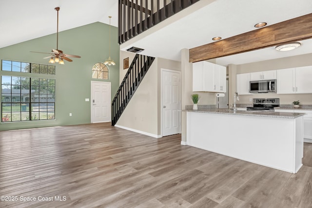 6827 Dodge Rd, Cocoa, FL 32927 - kitchen featuring appliances with stainless steel finishes, open floor plan, a ceiling fan, a high ceiling, and light wood-type flooring