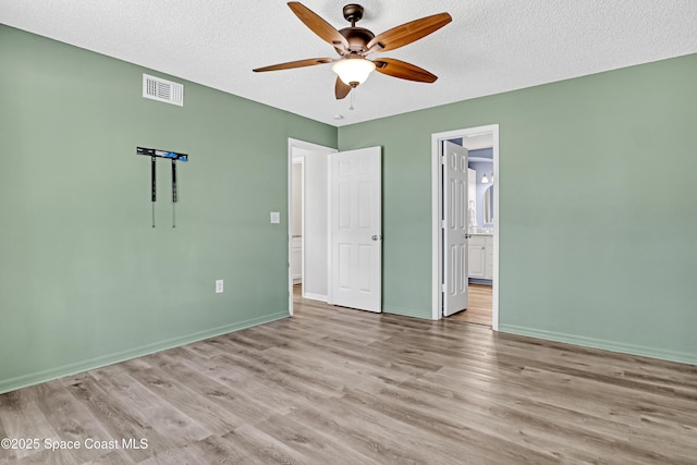6827 Dodge Rd, Cocoa, FL 32927 - unfurnished bedroom with wood finished floors, baseboards, a textured ceiling, connected bathroom, and a ceiling fan