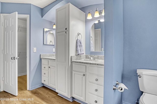 6827 Dodge Rd, Cocoa, FL 32927 - bathroom featuring vanity, wood finished floors, toilet, a walk in closet, and baseboards