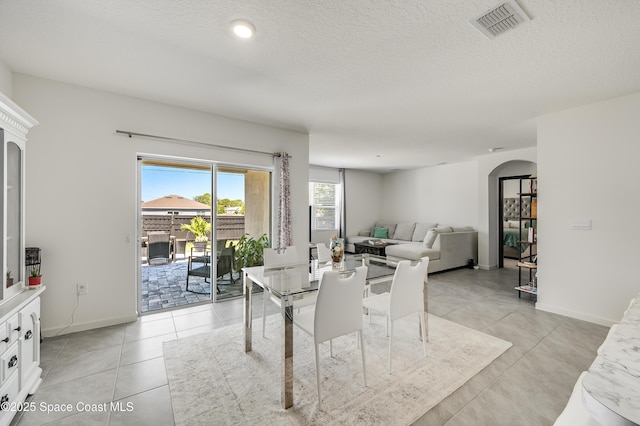 1460 Glendale Ave NW, Palm Bay, FL 32907 - dining room with arched walkways, baseboards, light tile patterned flooring, and a textured ceiling