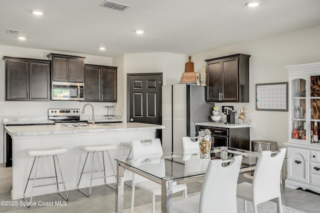 1460 Glendale Ave NW, Palm Bay, FL 32907 - kitchen featuring stainless steel appliances, a sink, dark brown cabinets, a breakfast bar, and an island with sink