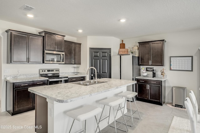 1460 Glendale Ave NW, Palm Bay, FL 32907 - kitchen featuring appliances with stainless steel finishes, a sink, dark brown cabinets, light countertops, and a breakfast bar