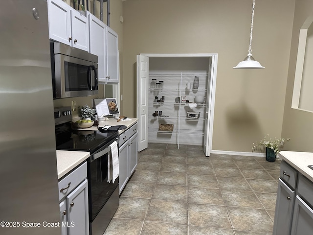2259 Cogan Dr, Palm Bay, FL 32909 - kitchen featuring stainless steel appliances, light countertops, hanging light fixtures, and baseboards