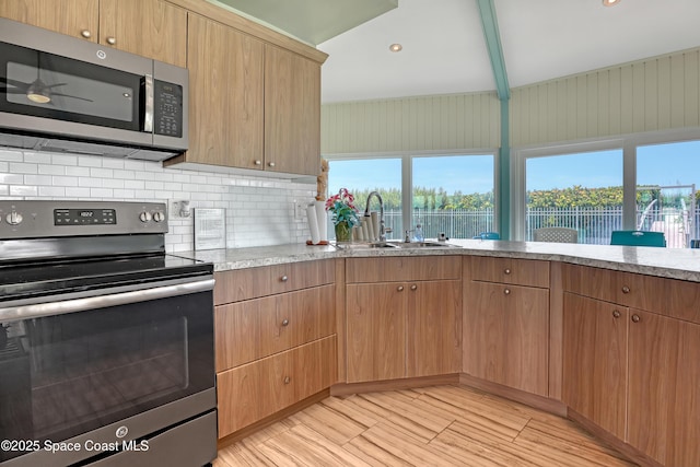 4000 Ocean Beach Blvd Unit 1J, Cocoa Beach, FL 32931 - kitchen featuring stainless steel appliances, a sink, decorative backsplash, light wood-style floors, and light stone countertops