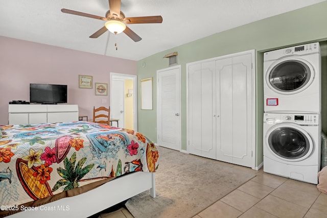 4000 Ocean Beach Blvd Unit 1J, Cocoa Beach, FL 32931 - bedroom with stacked washing machine and dryer, two closets, light tile patterned flooring, and a ceiling fan