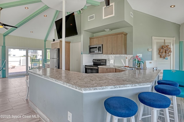 4000 Ocean Beach Blvd Unit 1J, Cocoa Beach, FL 32931 - kitchen featuring stainless steel appliances, a sink, a peninsula, high vaulted ceiling, and light brown cabinetry