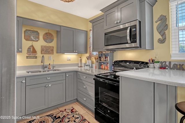 4000 Ocean Beach Blvd Unit 1J, Cocoa Beach, FL 32931 - kitchen with stainless steel microwave, black range with electric stovetop, a sink, and gray cabinets