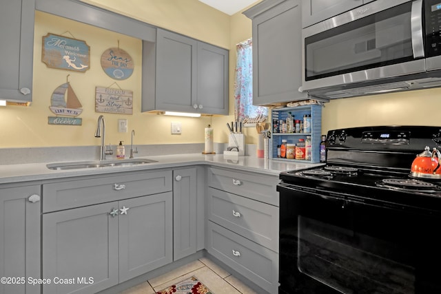 4000 Ocean Beach Blvd Unit 1J, Cocoa Beach, FL 32931 - kitchen with black electric range oven, stainless steel microwave, a sink, gray cabinetry, and light countertops