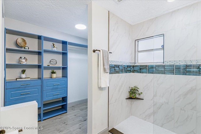 1020 Sycamore Dr, Rockledge, FL 32955 - bathroom with a textured ceiling, wood finished floors, and a tile shower