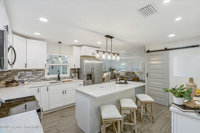 1020 Sycamore Dr, Rockledge, FL 32955 - kitchen featuring stainless steel appliances, a sink, a barn door, light wood-style flooring, and plenty of natural light