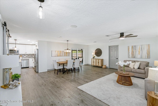 1020 Sycamore Dr, Rockledge, FL 32955 - living area featuring light wood-style floors, ceiling fan, a textured ceiling, a chandelier, and baseboards