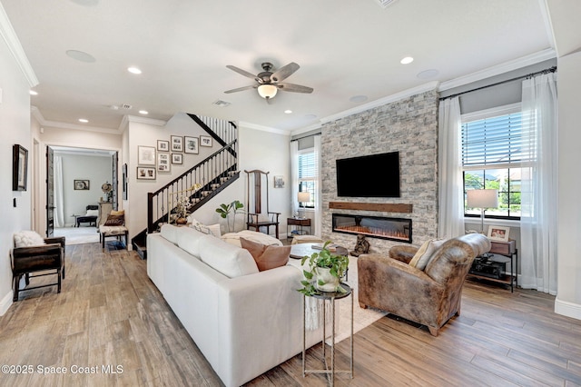 2291 Trava Ln, Melbourne, FL 32940 - living room with stairs, light wood finished floors, ornamental molding, a stone fireplace, and a ceiling fan