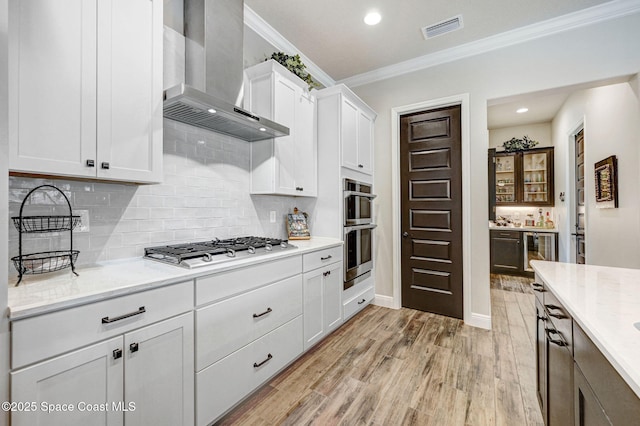 2291 Trava Ln, Melbourne, FL 32940 - kitchen featuring wall chimney range hood, appliances with stainless steel finishes, crown molding, beverage cooler, and white cabinetry