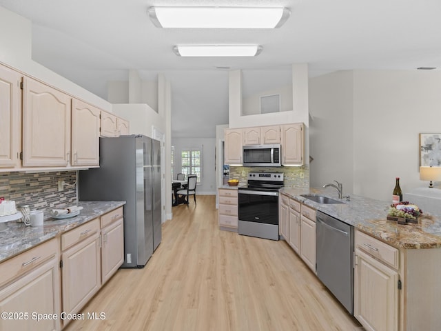 1750 Old Glory Blvd, Melbourne, FL 32940 - kitchen with appliances with stainless steel finishes, a peninsula, light wood-style floors, tasteful backsplash, and light stone countertops