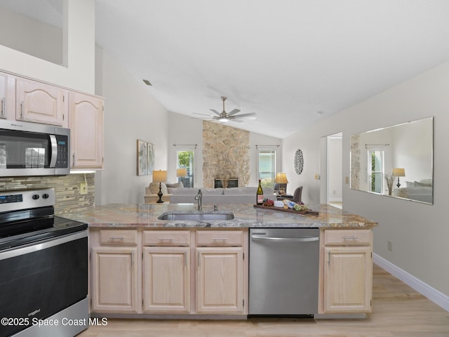 1750 Old Glory Blvd, Melbourne, FL 32940 - kitchen with stainless steel appliances, a sink, light brown cabinetry, open floor plan, and vaulted ceiling