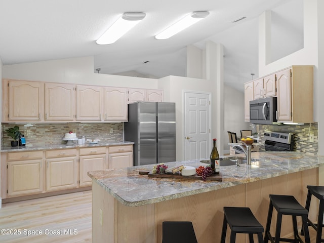 1750 Old Glory Blvd, Melbourne, FL 32940 - kitchen with appliances with stainless steel finishes, light brown cabinetry, a peninsula, tasteful backsplash, and high vaulted ceiling