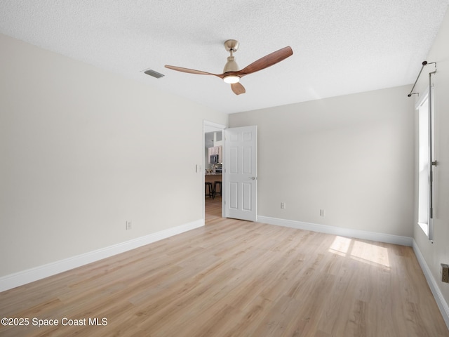 1750 Old Glory Blvd, Melbourne, FL 32940 - unfurnished room with plenty of natural light, a ceiling fan, light wood-style flooring, baseboards, and a textured ceiling