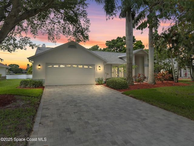 1750 Old Glory Blvd, Melbourne, FL 32940 - view of front of house featuring an attached garage, stucco siding, decorative driveway, and a lawn