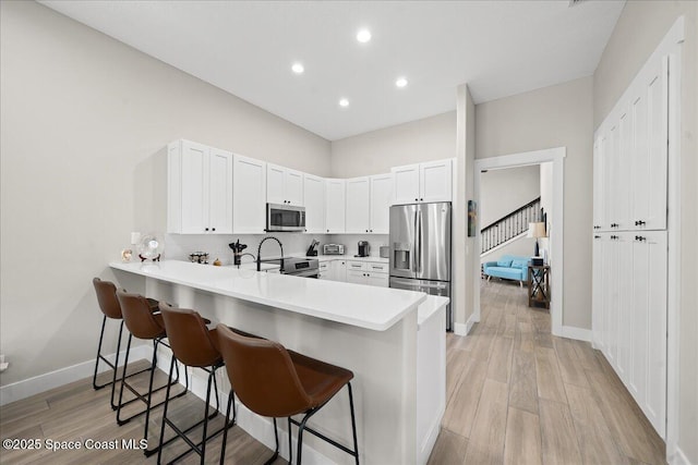 120 Mediterranean Way, Indian Harbour Beach, FL 32937 - kitchen with appliances with stainless steel finishes, a kitchen breakfast bar, a peninsula, light countertops, and recessed lighting