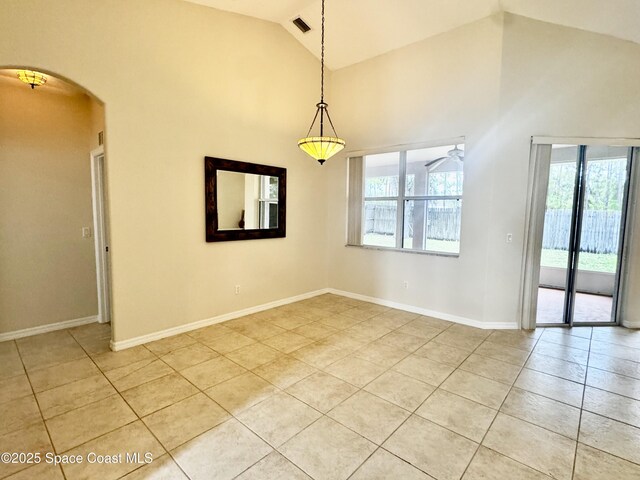 2601 Diane Ave SE, Palm Bay, FL 32909 - empty room with light tile patterned flooring, arched walkways, high vaulted ceiling, and baseboards