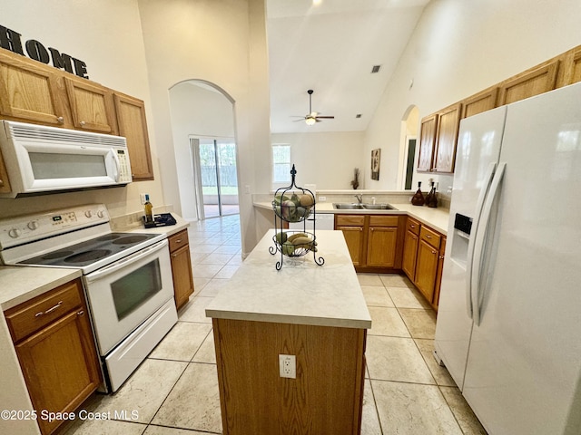 2601 Diane Ave SE, Palm Bay, FL 32909 - kitchen featuring white appliances, arched walkways, a kitchen island, a sink, and high vaulted ceiling