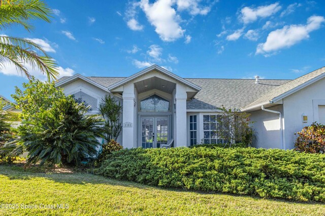 1181 Cypress Trace Dr, Melbourne, FL 32940 - view of front of property with stucco siding, roof with shingles, a front yard, and french doors