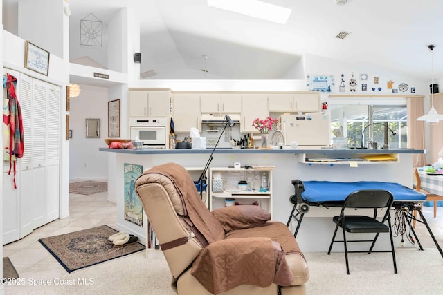 1181 Cypress Trace Dr, Melbourne, FL 32940 - kitchen with white appliances, white cabinets, pendant lighting, a skylight, and a kitchen breakfast bar