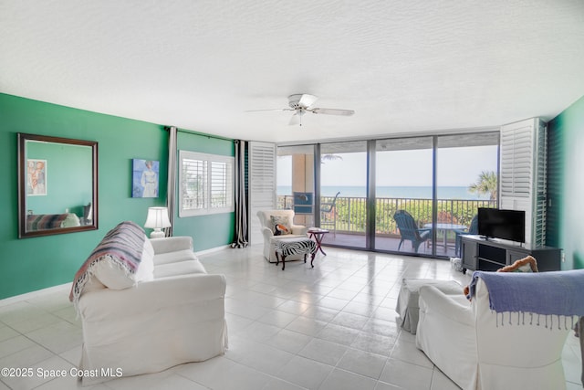 1527 S Atlantic Ave Unit 201, Cocoa Beach, FL 32931 - living area with a wall of windows, baseboards, ceiling fan, light tile patterned flooring, and a textured ceiling